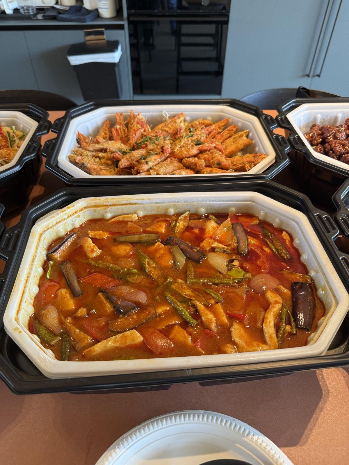 Overhead view of self-heating trays holding curry and sweet-and-sour dishes
